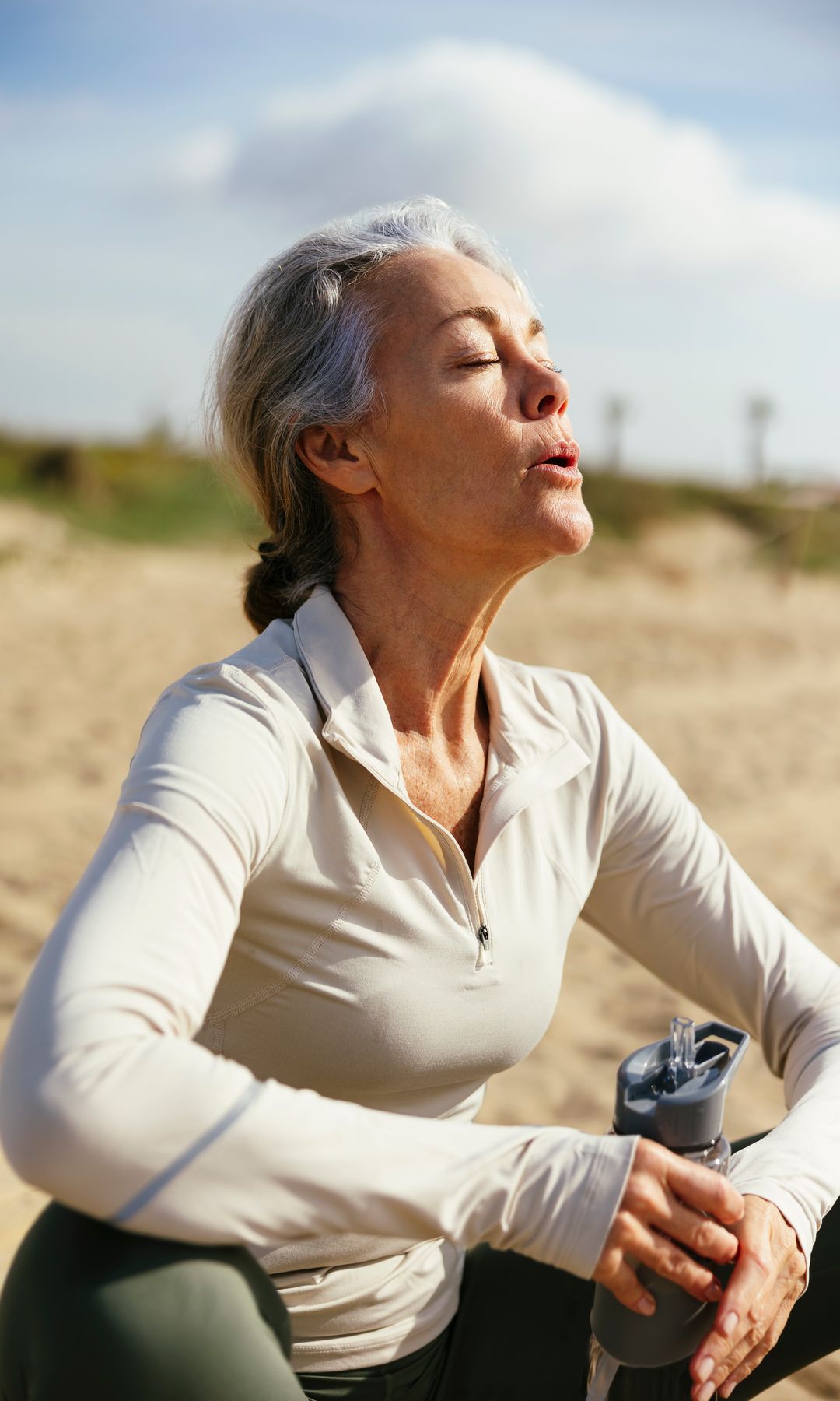 Una mujer de más de 50 años descansando en la playa tras un paseo