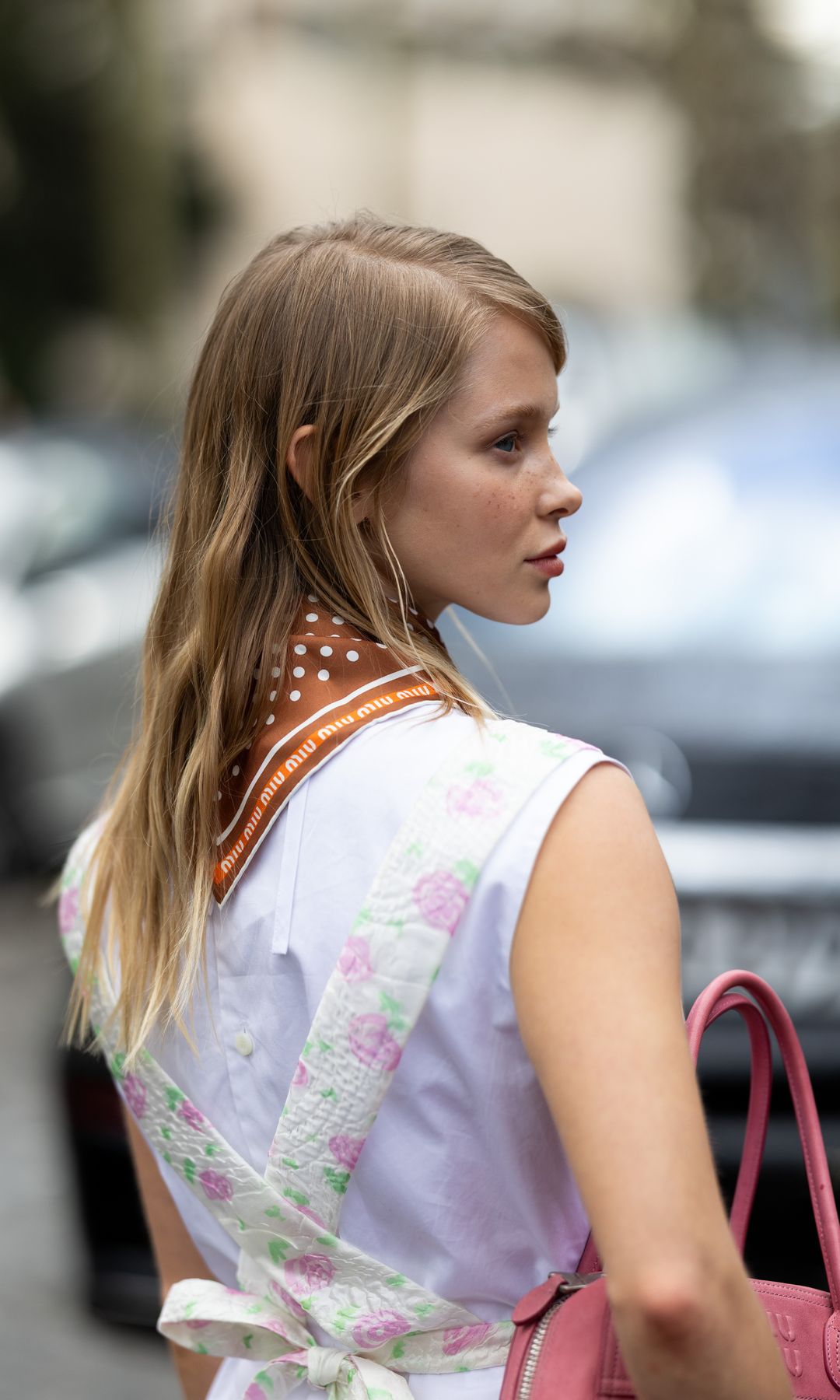 PARIS, FRANCE - MARCH 10: Alla Bruletova wears a white short mini dress, a brown polka dots printed scarf, a pink leather Miu Miu bag and a white floral printed apron outside Miu Miu show during Day Nine of Paris Fashion Week - Womenswear Fall/Winter 2026/2027 on March 10, 2026 in Paris, France