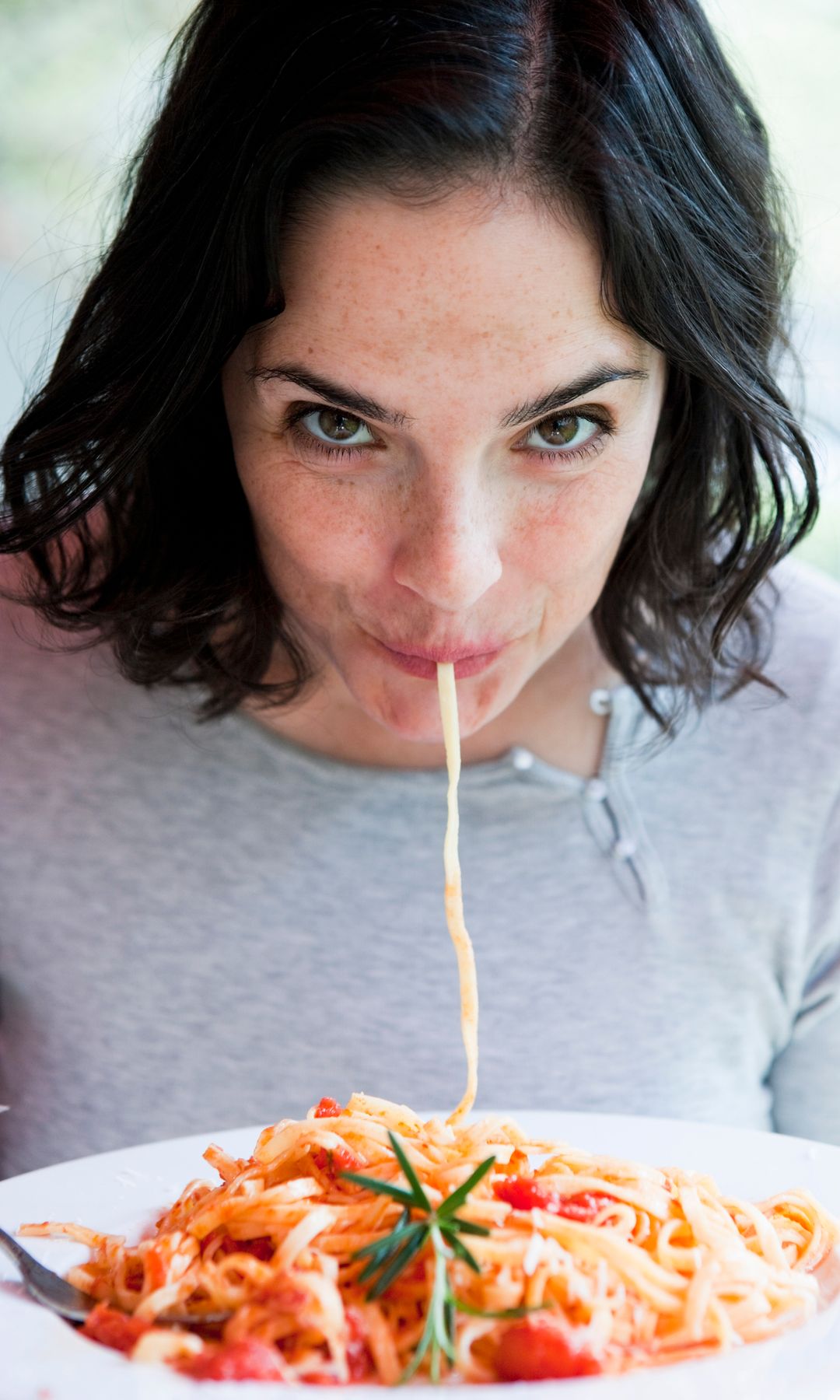 Mujer comiendo espagueti con queso parmesano