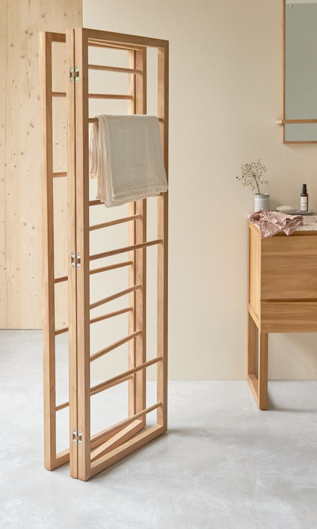 Baño con biombo de madera, mueble de lavabo de madera y cesto