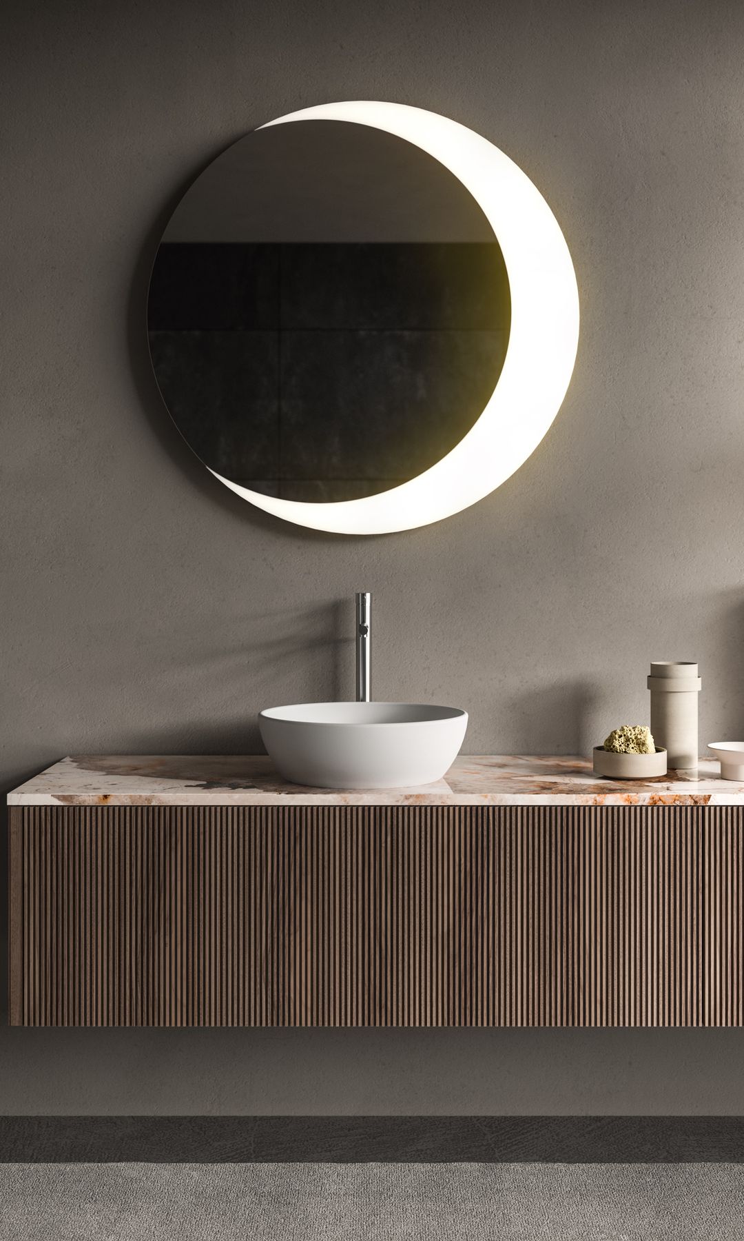 Baño con mueble suspendido de madera, espejo redondo, lavabo sobre encimera redondo y accesorios sobre la encimera 