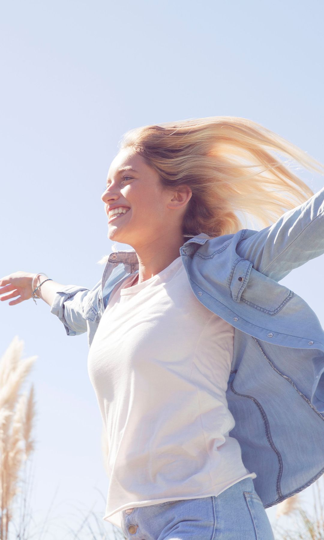 Mujer con los brazos levantados sonriendo al sol