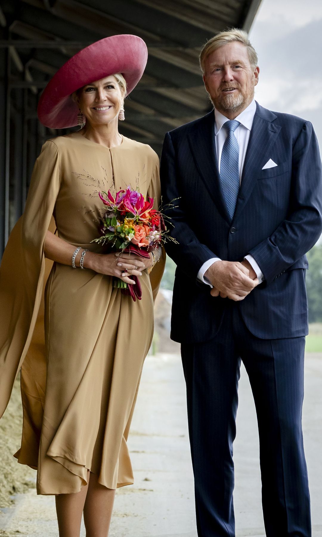 Máxima de Holanda lleva la elegancia al campo: vestido capa, pamela XL y pendientes de borlas para visitar una granja de vacas