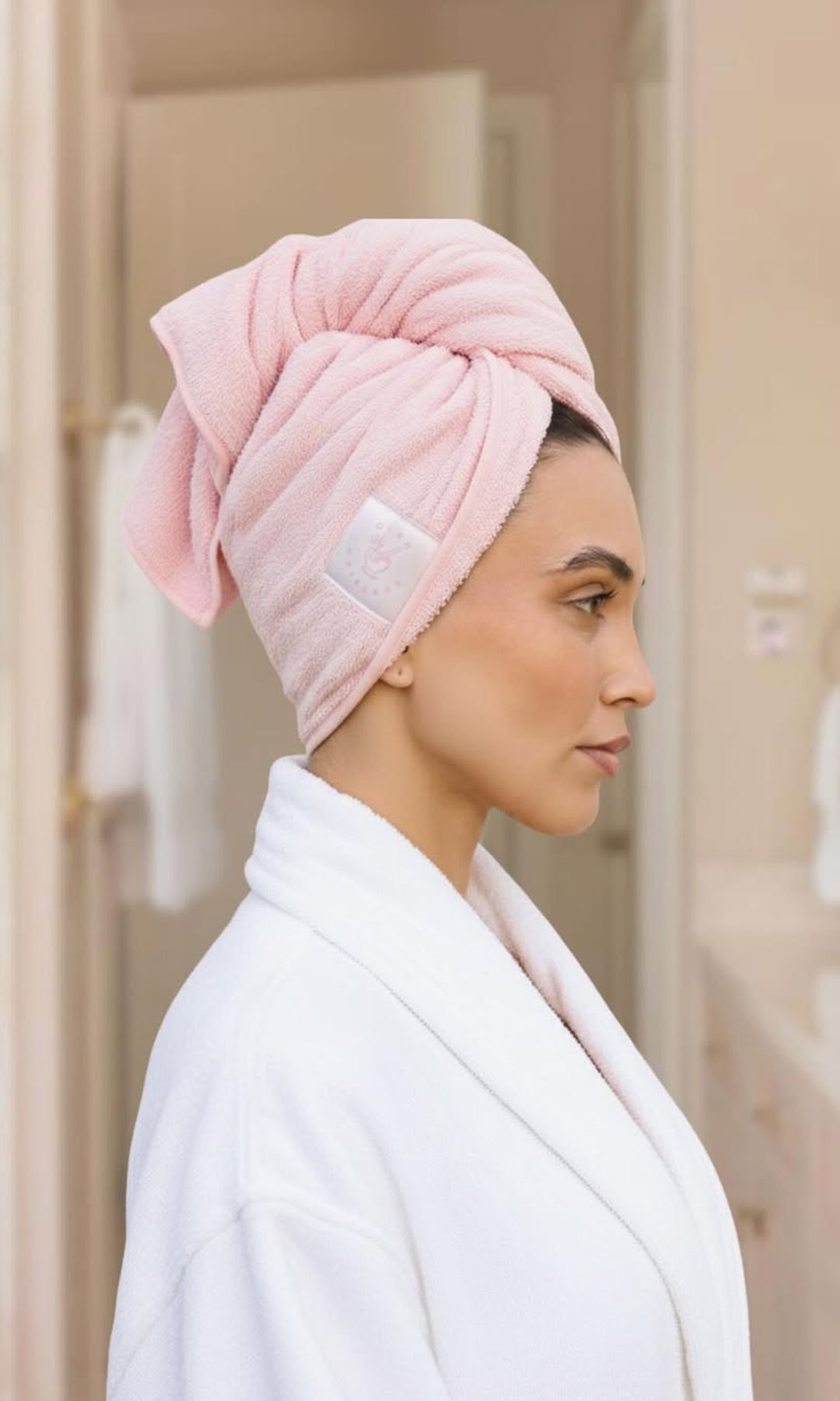 Mujer con el cabello envuelto en una toalla rosa de microfibra después de la ducha.