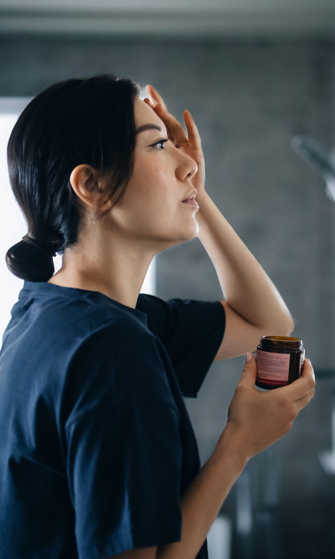 Una mujer asiática aplicándose un sérum
