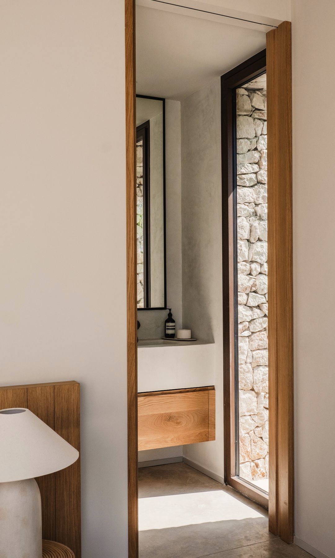 Baño integrado en el dormitorio con mueble de madera, puerta de cristal con salida al exterior 