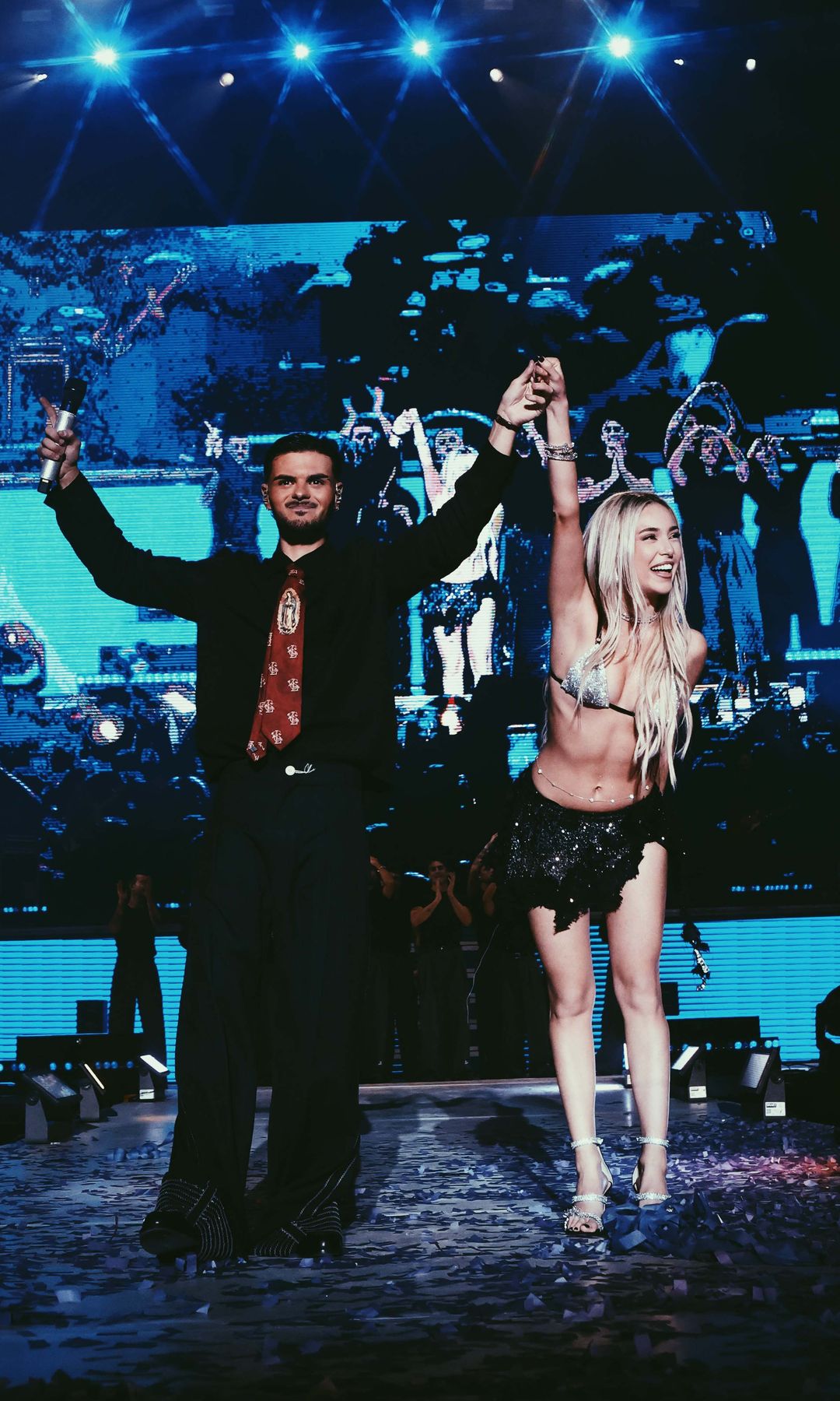 Abraham Mateo y Ana Mena en un escenario, celebrando con los brazos levantados.