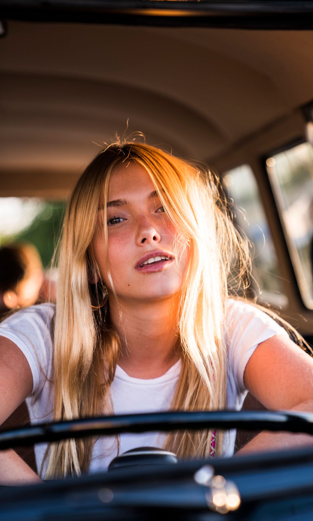 Chica joven en el coche a la luz del sol