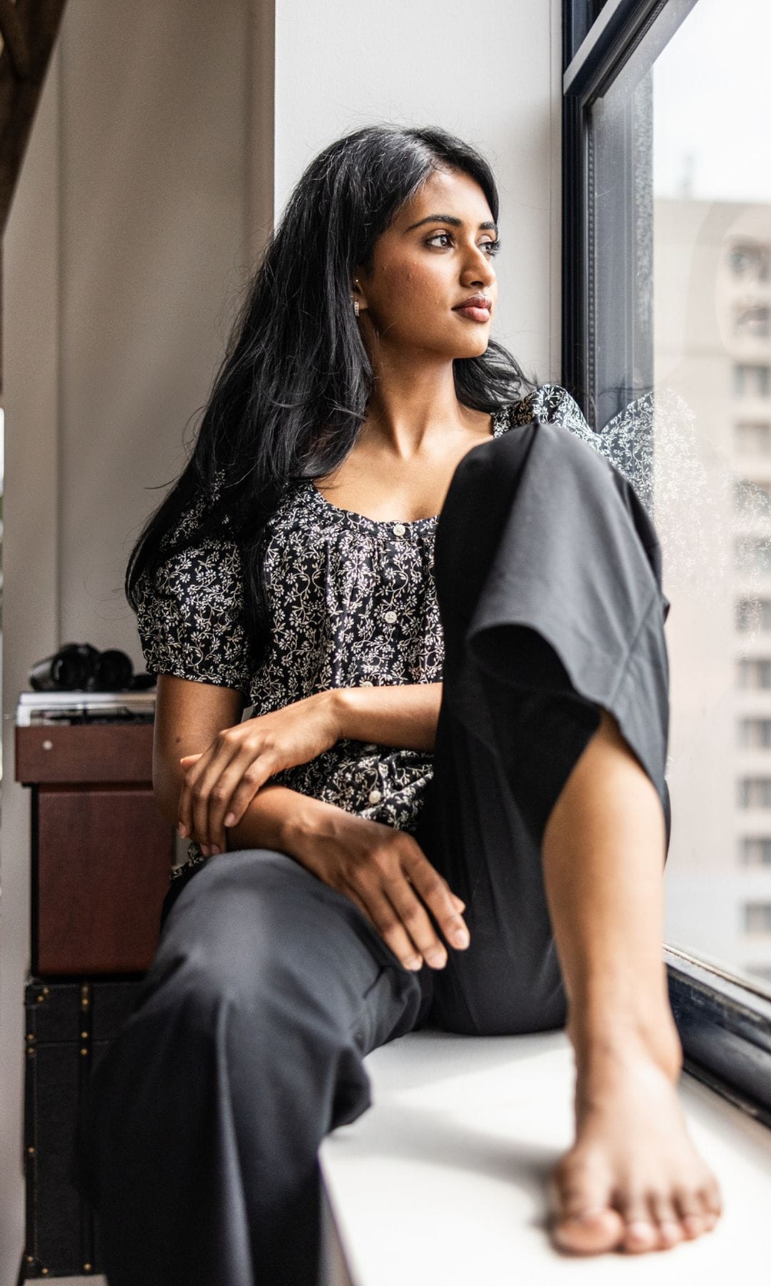 Mujer joven india mirando por la ventana con expresión serena