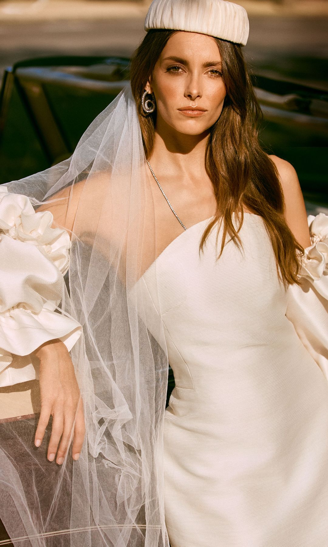 Un giro original: Las mangas globo desmontables  son las protagonistas de este vestido de líneas rectas y abertura en la espalda, de María Barragán. Como accesorios, la modelo lleva casquete de gasa fruncida, de Mimoki, pendientes de cristal, de Swarovski, y collar de oro blanco y diamantes, de Ansorena