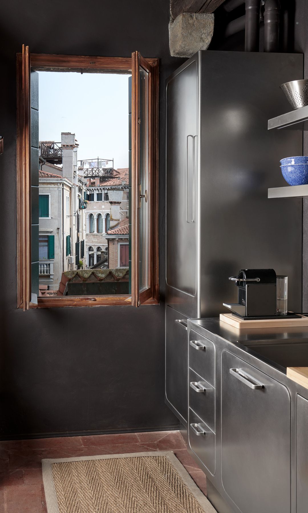 Cocina de acero con ventana de madera, frigorífico de acero inoxidable, suelo de madera y alfombra 