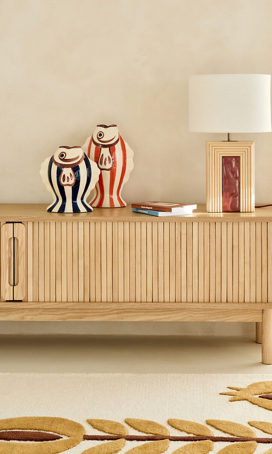 Mueble bajo de madera con puertas de madera en lamas, lámpara de techo, jarrones, alfombra