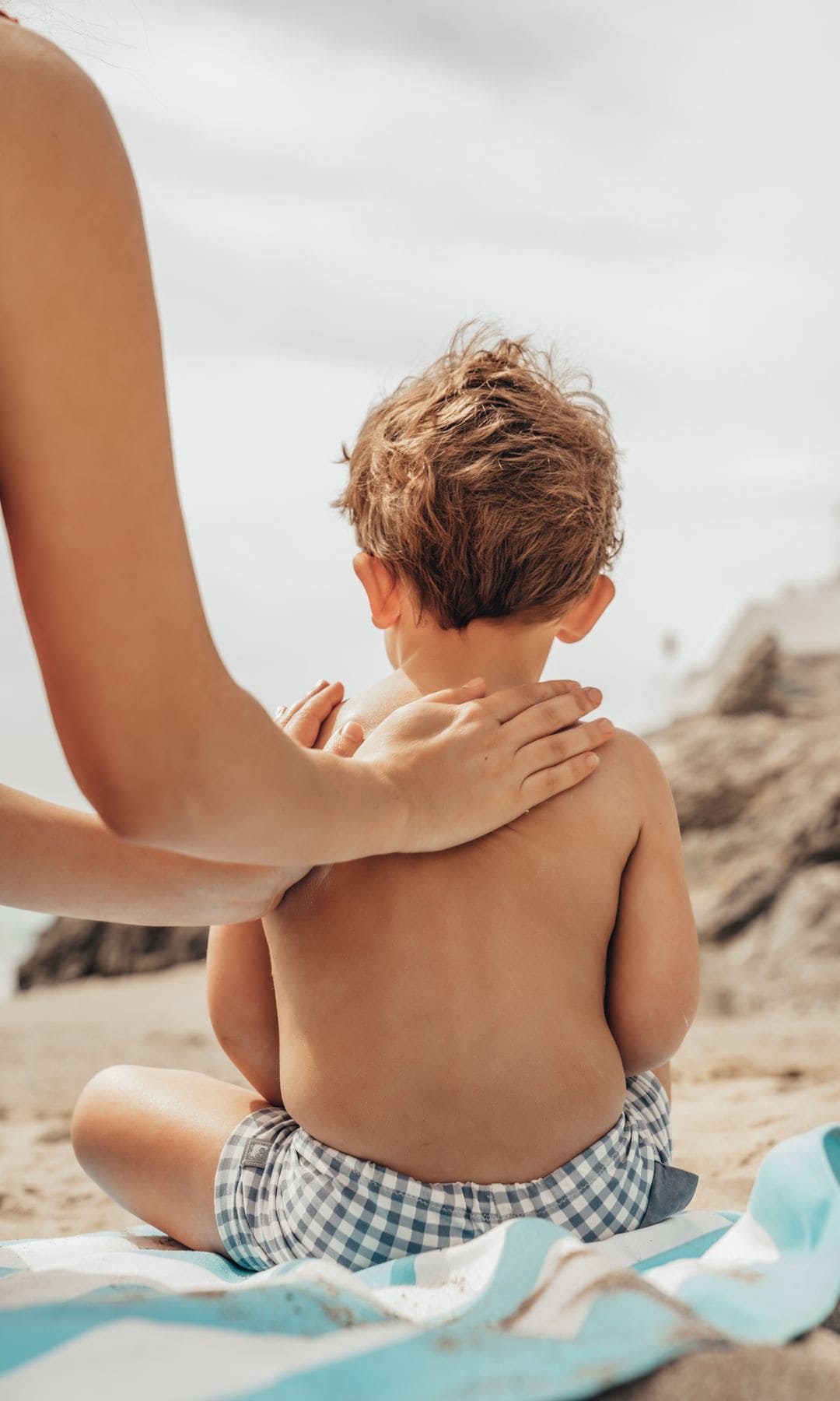 Madre aplica protector solar a su hijo