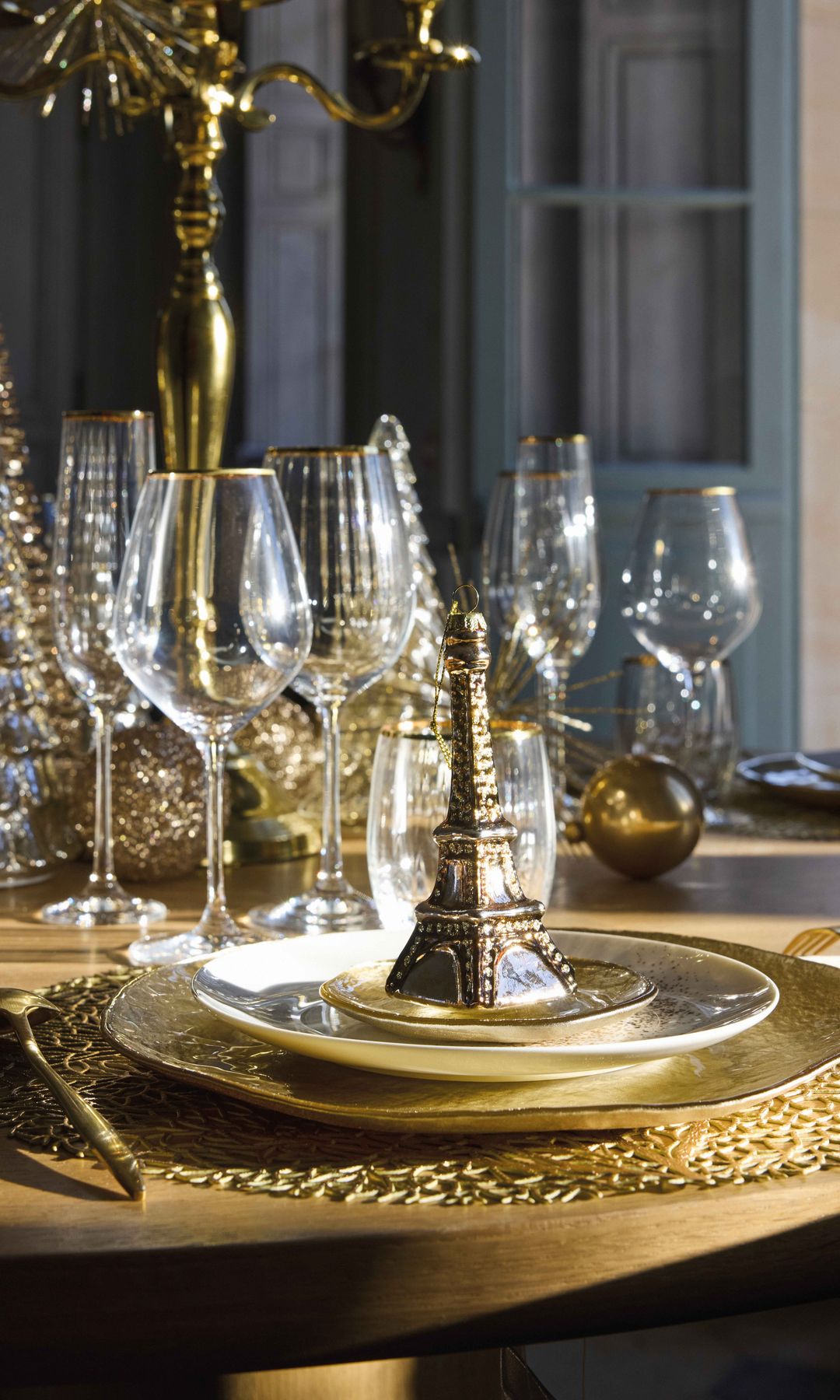 Mesa de Nochevieja con manteles individuales dorados, copas con el filo dorado, candelabro dorado, cubiertos dorados 