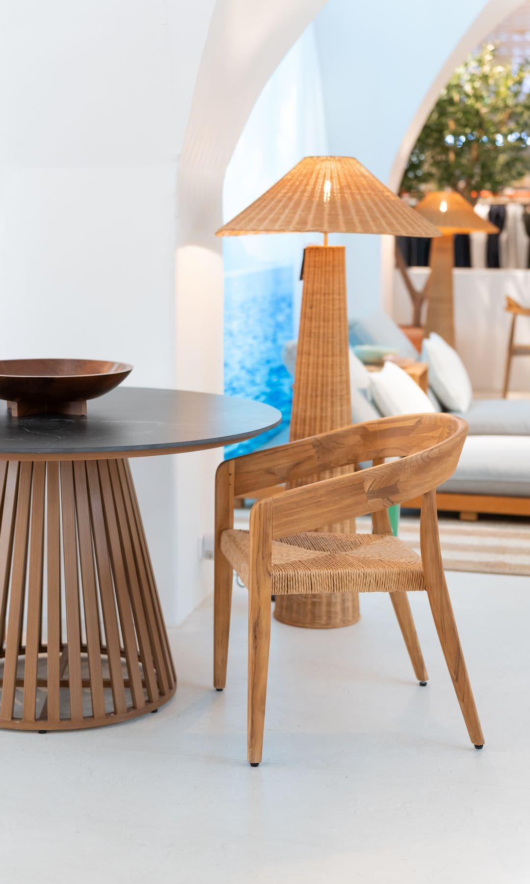 Mesa redonda de madera, silla con el asiento de enea y lámpara de pie de ratán