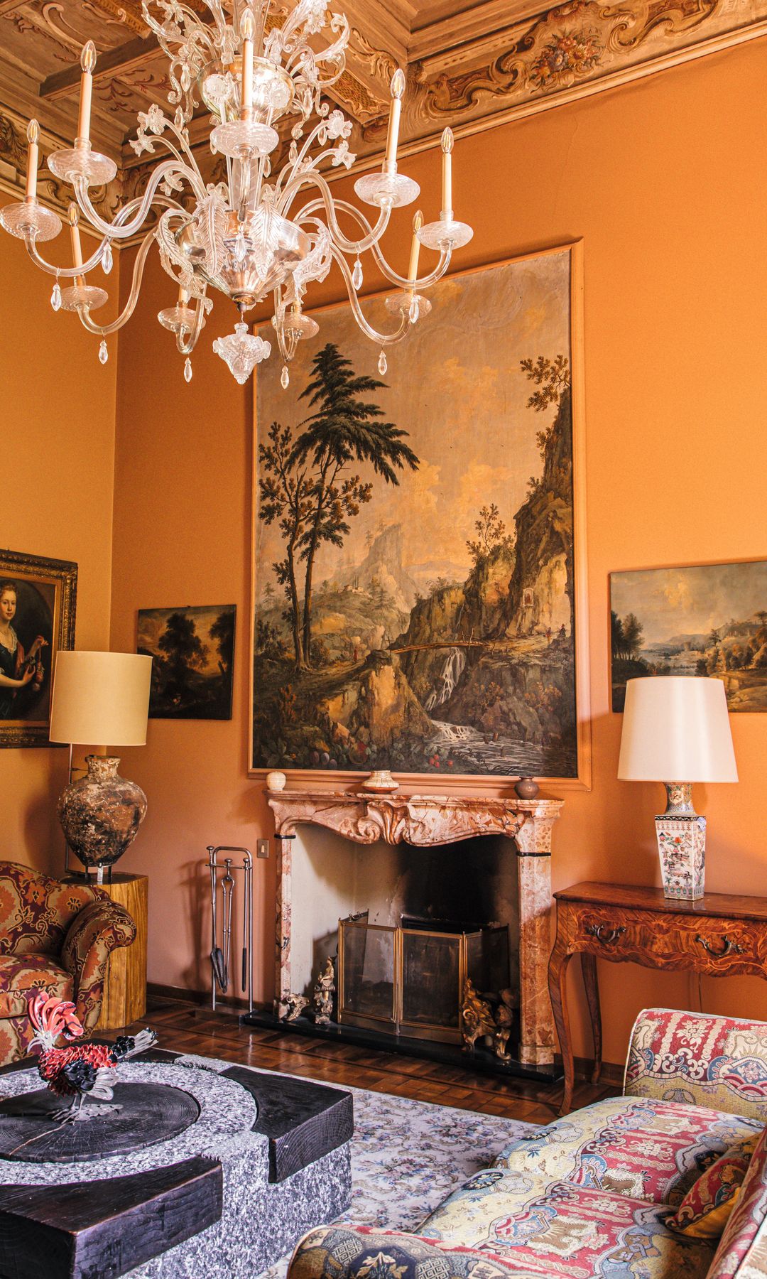 Dos imágenes de otro de los salones, con chimenea de mármol rosa del año 1700 y, sobre ella, una pintura que data del mismo año y dos óleos de 1800. La mesa está hecha con piedra de un antiguo molino