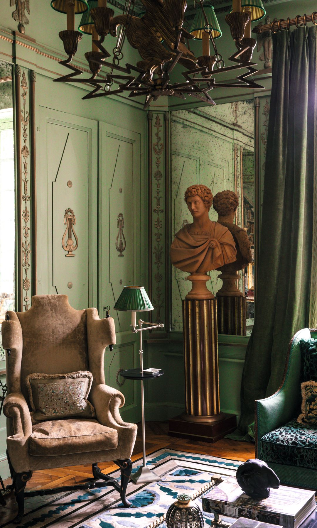 Sala con sillón, lámpara, busto y espejo