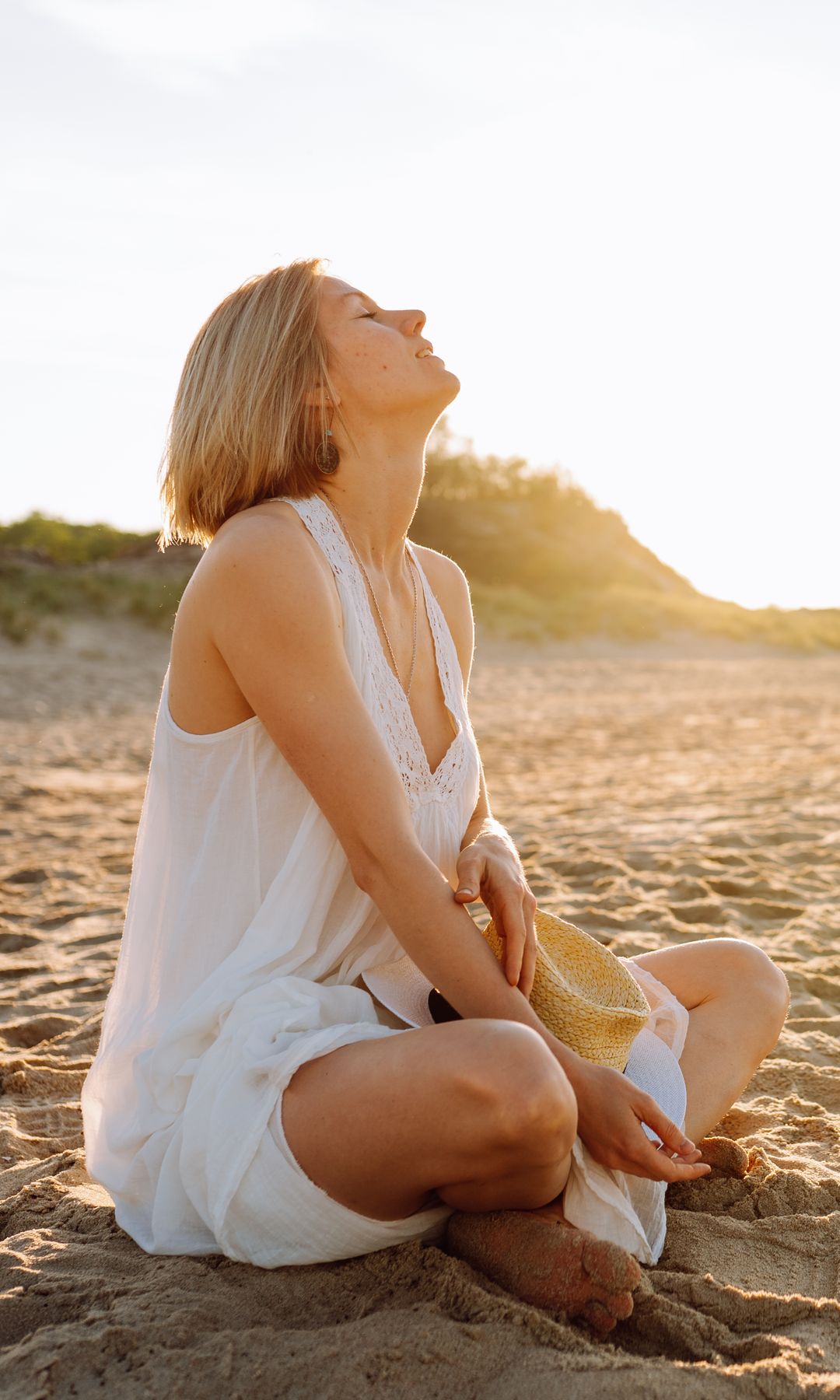 mujer sentada en la playa relajada
