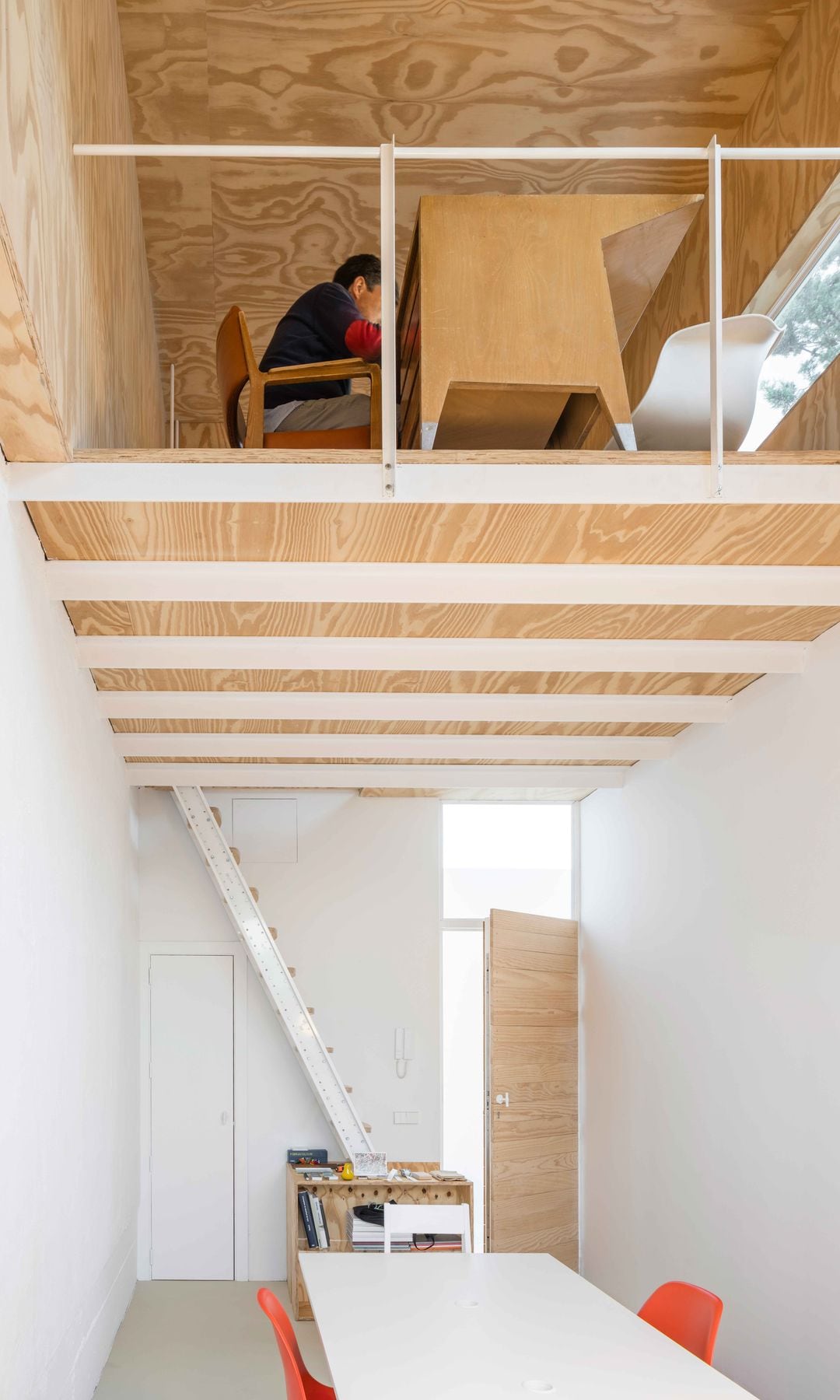 Casa de madera con altillo en la planta superior donde se ha habilitado un despacho, hombre trabajando 