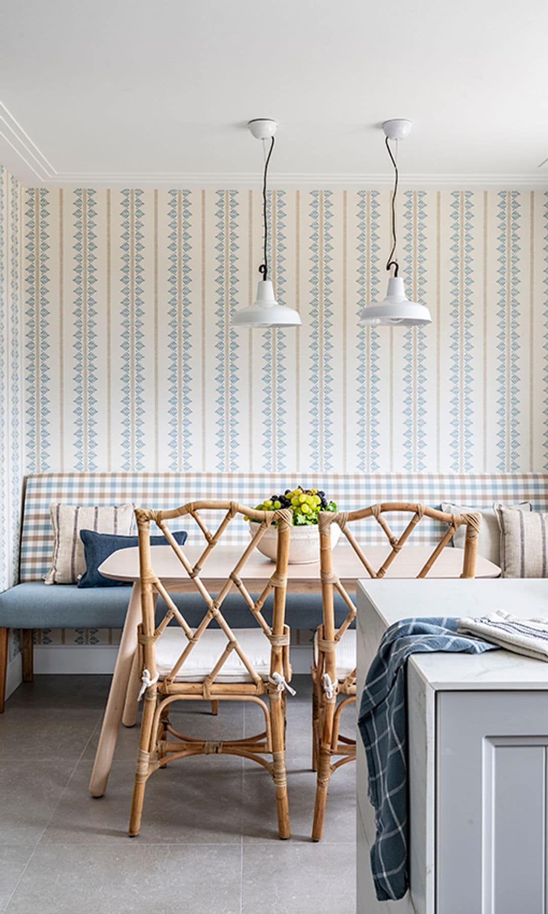 Cocina con office y papel pintado, banco con respaldo tapizado, sillas de fibras vegetales, lámparas de techo