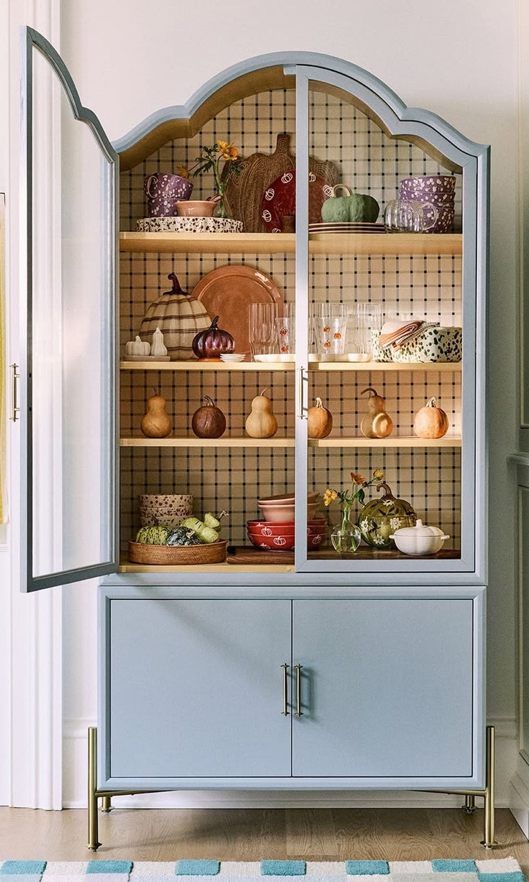 Vitrina azul pastel con vajilla artesanal y frutas expuestas.