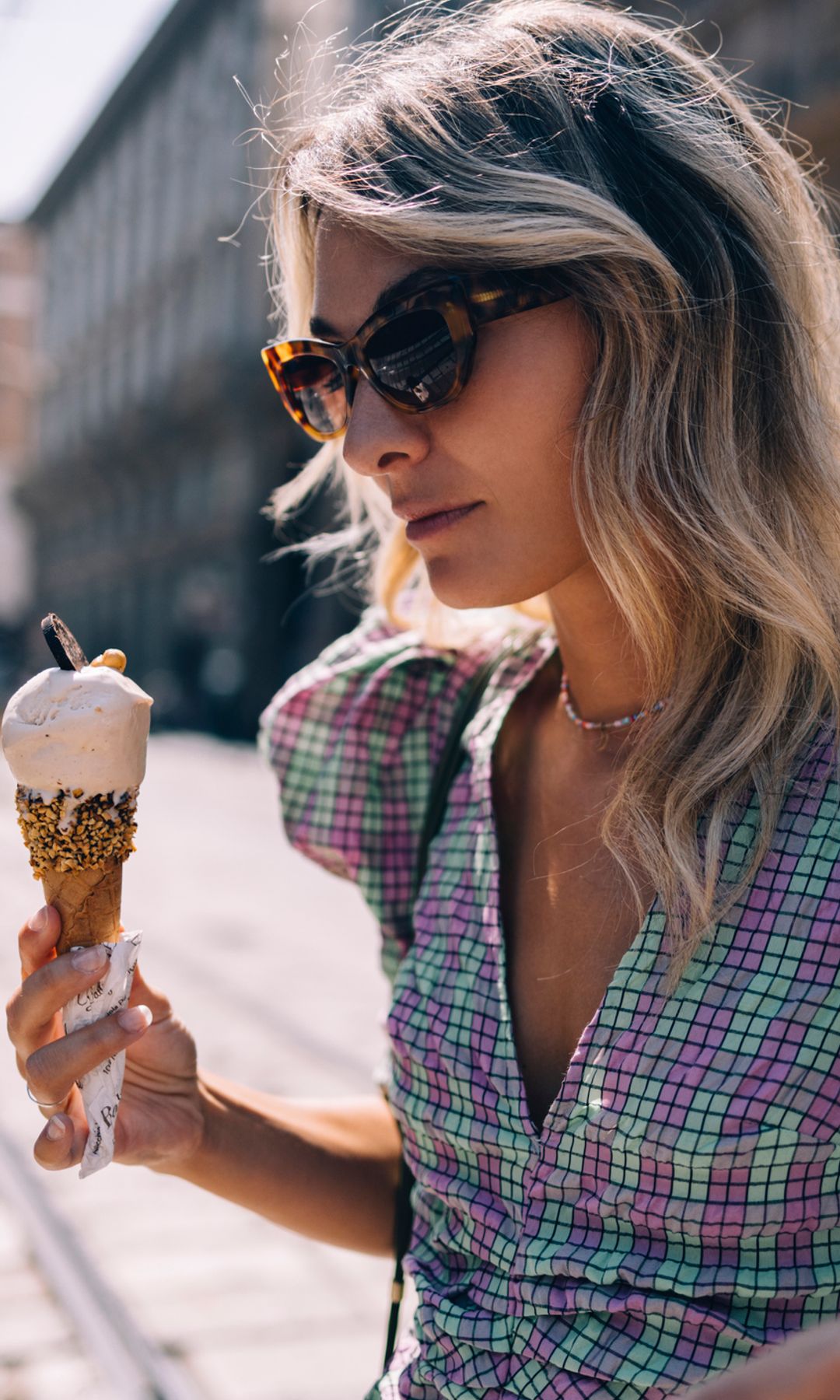 mujer seria con un helado en las manos caminando por la ciudad