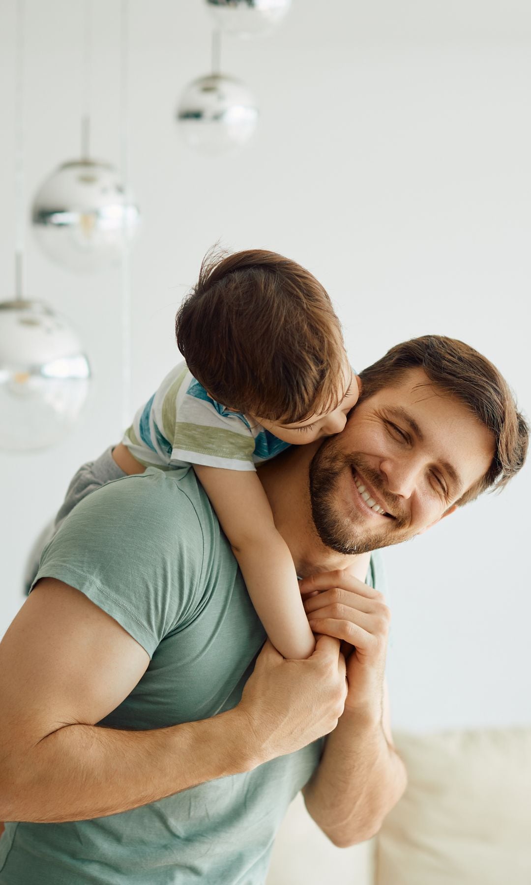 Un hijo besa a su padre con la inocencia más pura, mientras este le coge a caballito