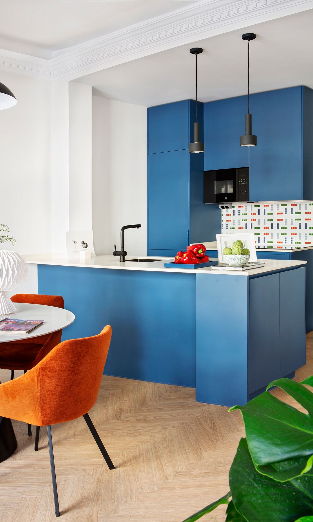 Cocina con comedor, muebles azules oscuro. isla a modo de barra, antepecho de azulejos 