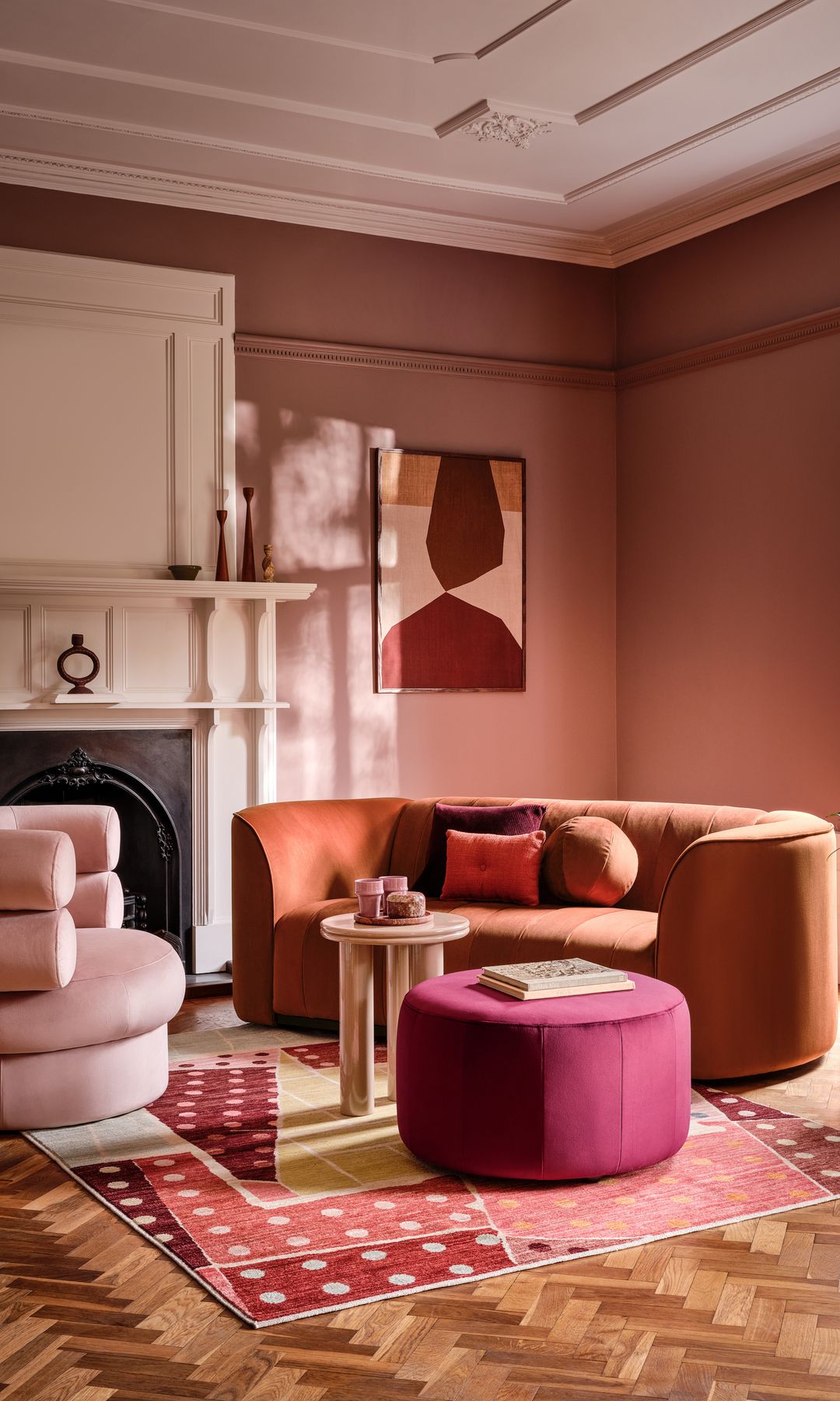 Salón con chimenea, sofá marrón, molduras en el techo, alfombra, mesa de centro tapizada, butaca rosa empolvado