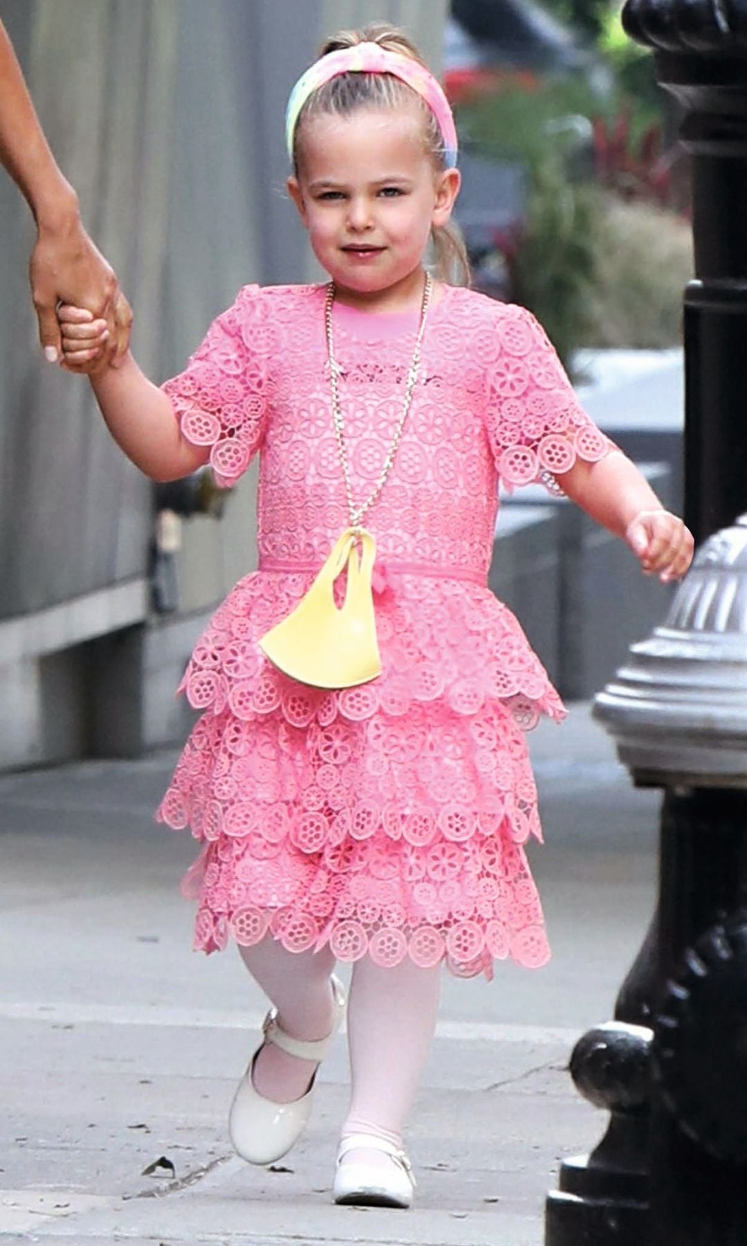 Irina Shayk, con vestido corto marrón y botas, camina con su hija, vestida de rosa, tomadas de la mano.