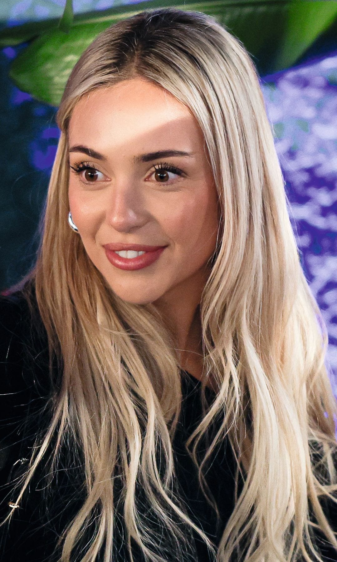 Ana Mena sonriendo con cabello largo rubio y ropa negra