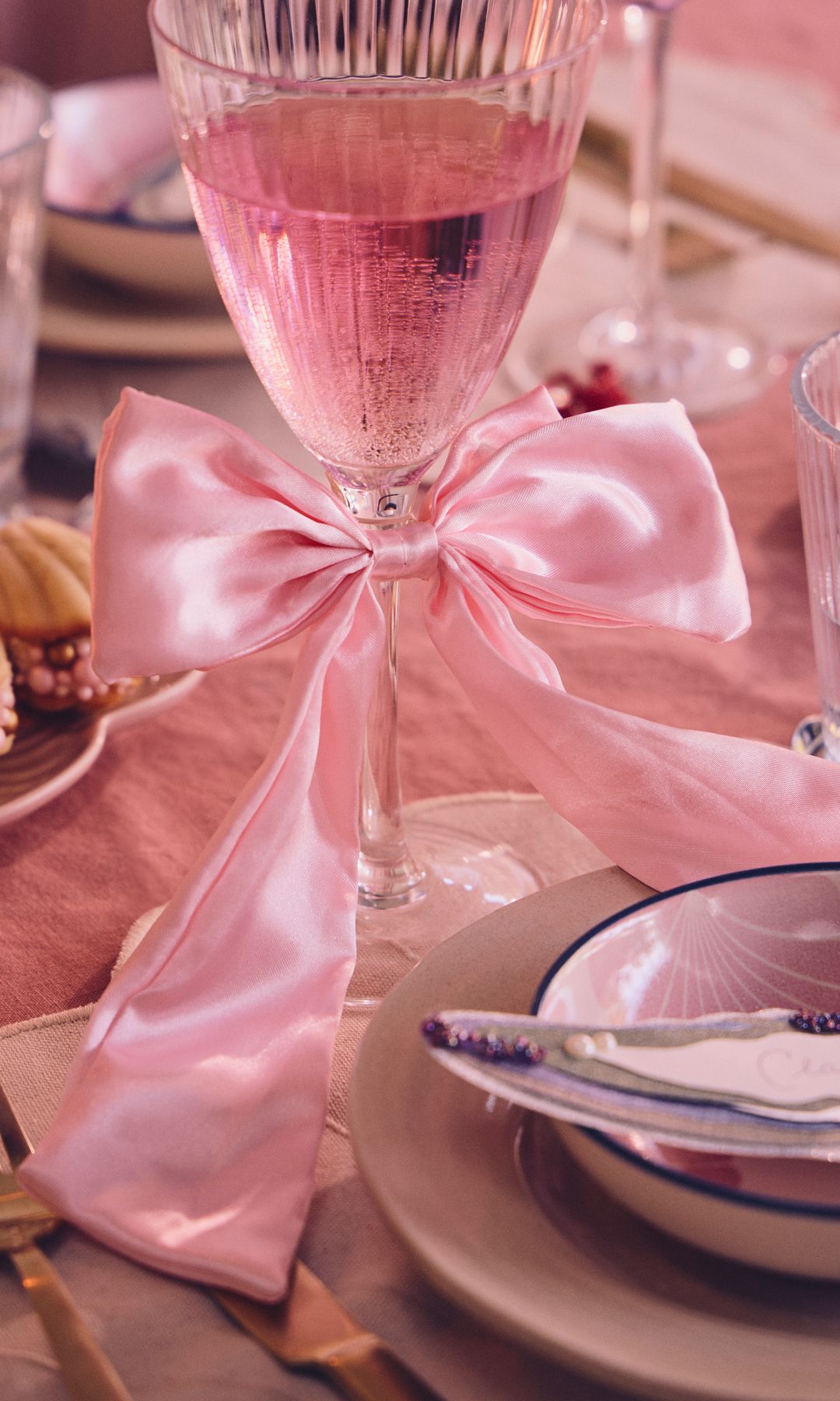 Mesa de Navidad en color rosa, con copas, manteles y adornos de lazo de color rosa