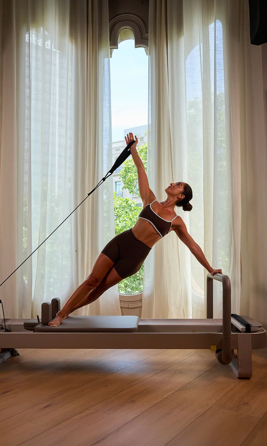 Mujer realizando un ejercicio de Pilates con resistencia sobre una máquina reformer