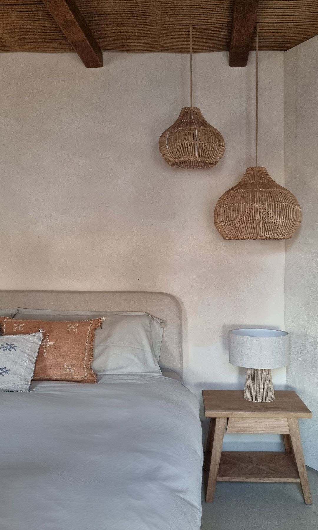 Dormitorio con lámparas de fibras vegetales, techo de mimbre, paredes encaladas, cabecero tapizado, paredes cal