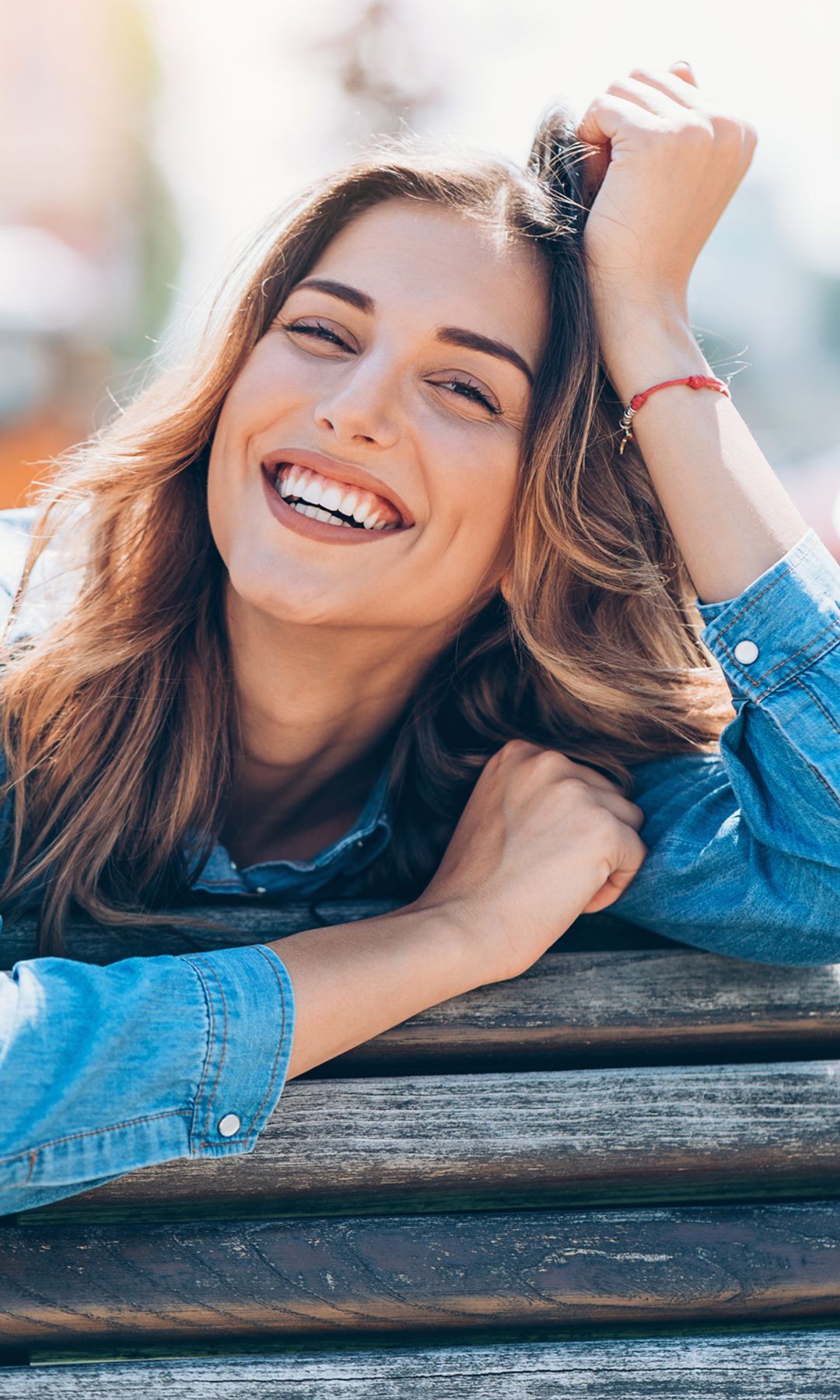 Mujer feliz y riéndose sentada en un banco en el exterior