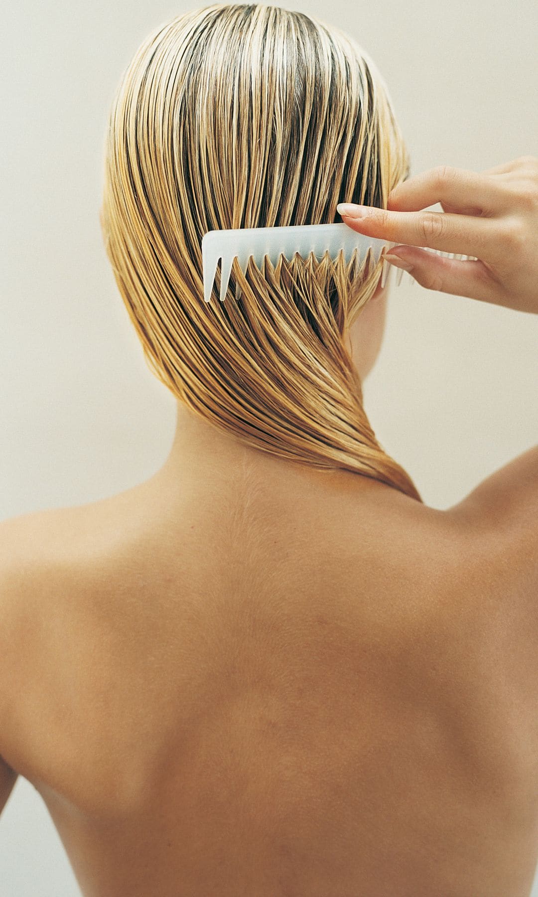 Mujer rubia espaldas peine blanco pelo