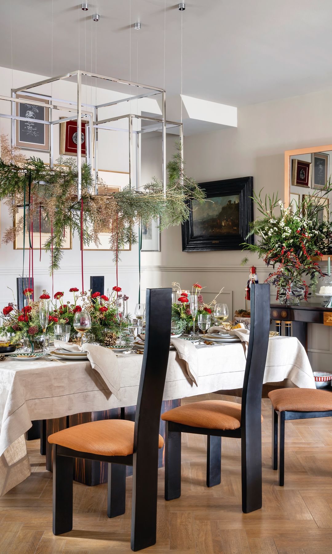 Comedor con mesa de Navidad con centros de flores rojas, decoración con plantas verdes que cuelgan de la lámpara de techo