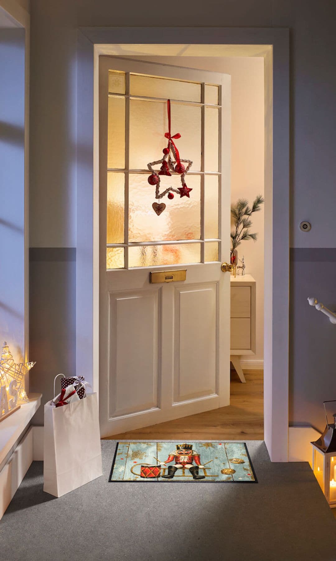 Entrada puerta casa con corona de navidad, felpudo navideño, casitas de Navidad con luces, farolillos