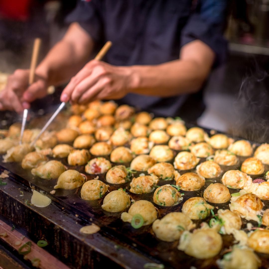 Cocinanto takoyaki en la ciudad de Osaka, Japón