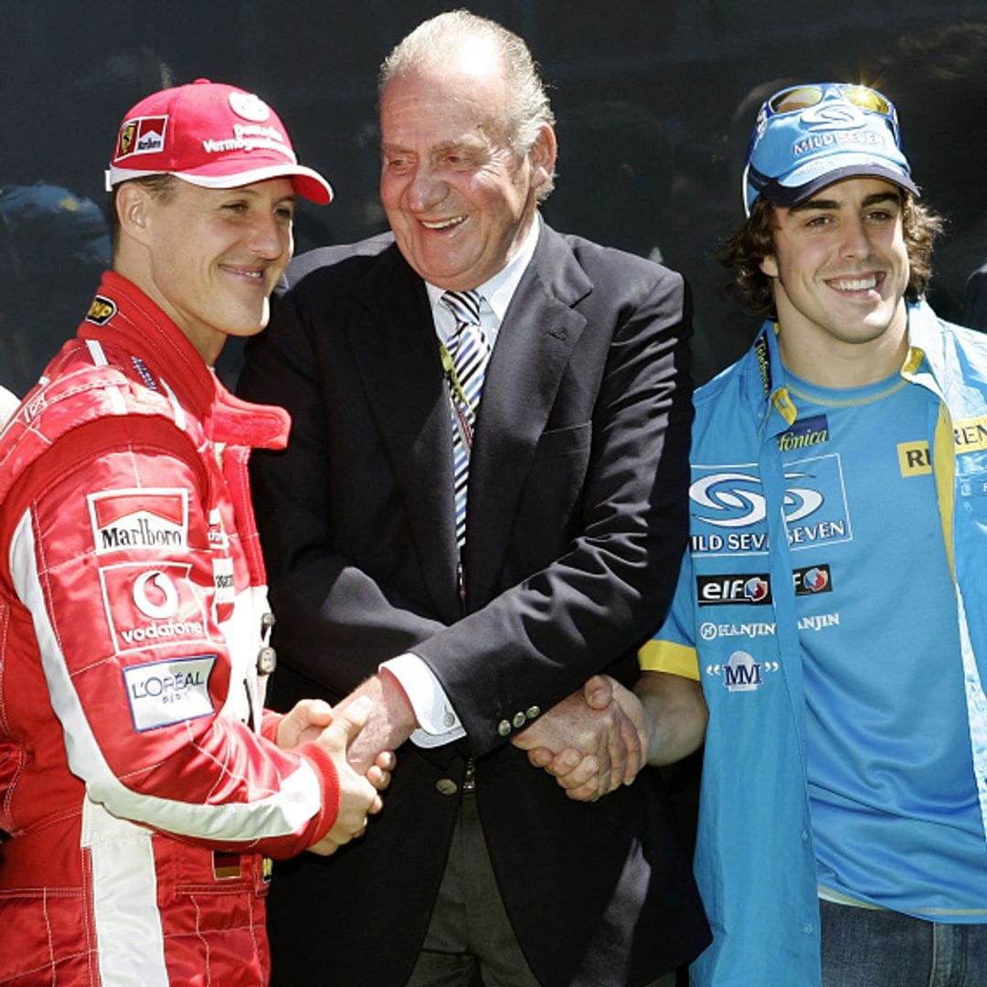 El rey de España, Juan Carlos, estrechando la mano de Michael Schumacher, cuando pilotaba en Ferrari, y del piloto Fernando Alonso, cuando estaba en Renault, durante el circuito del Gran Premio de España, 2005
