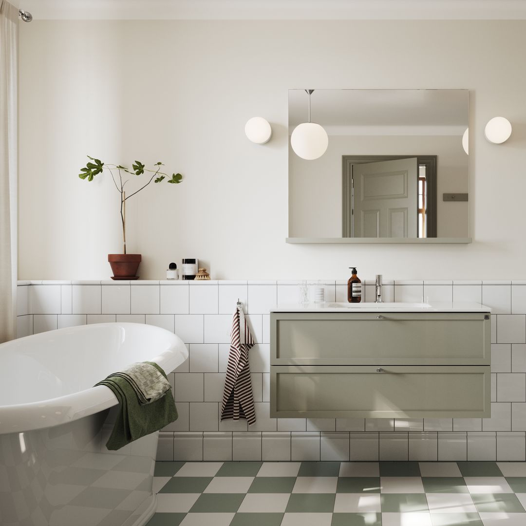 Baño con bañera con zócalo alto de azulejos blancos, mueble verde suspendido, bañera exenta, suelo de baldosas blancas y verdes, espejo, apliques redondos a ambos lados del espejo