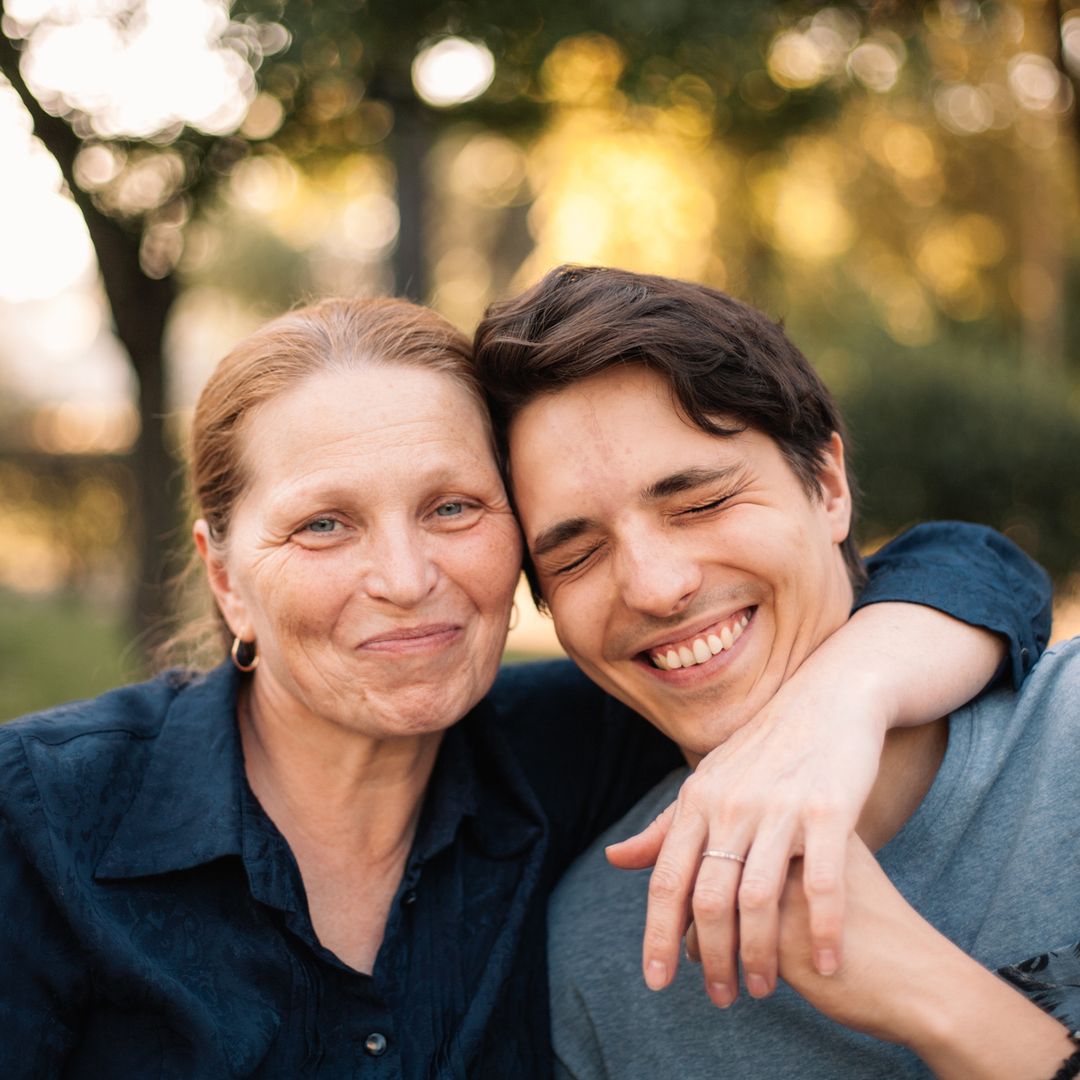 Madre abraza a su hijo, ya adulto