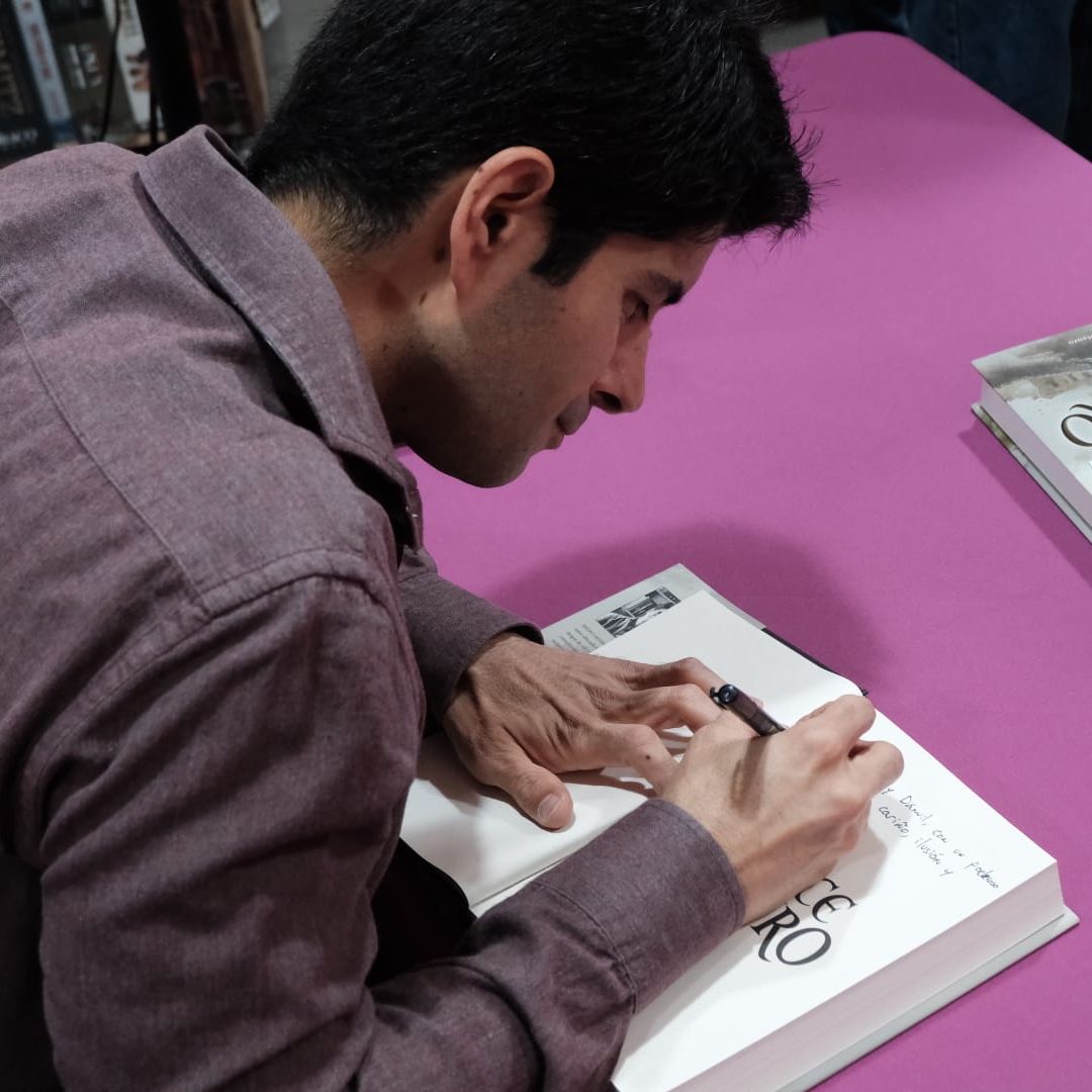 Mauro Caffaratto, hijo de Almudena Grandes, concentrado mientars firma sus libros 
