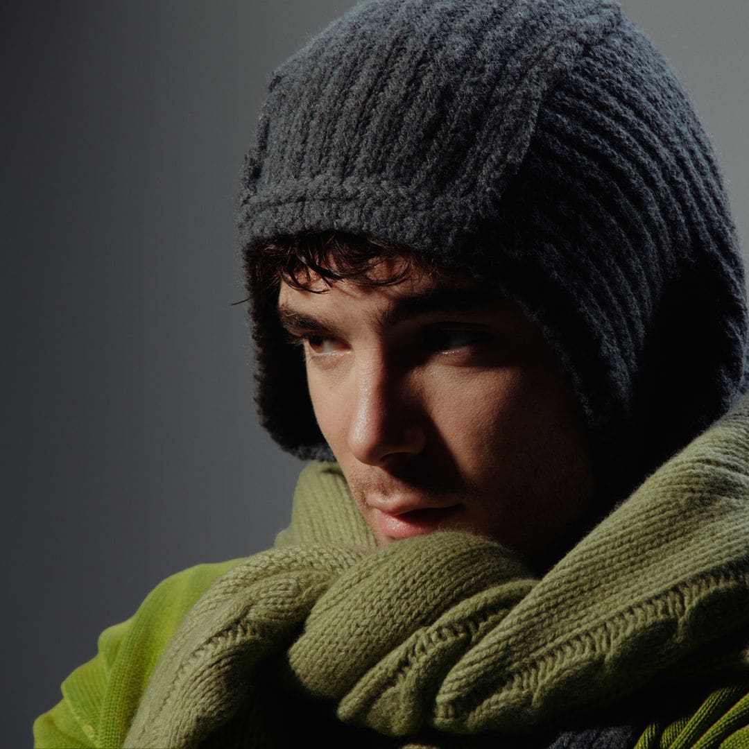 Ters con gorro gris y bufanda verde, mirando hacia un lado.