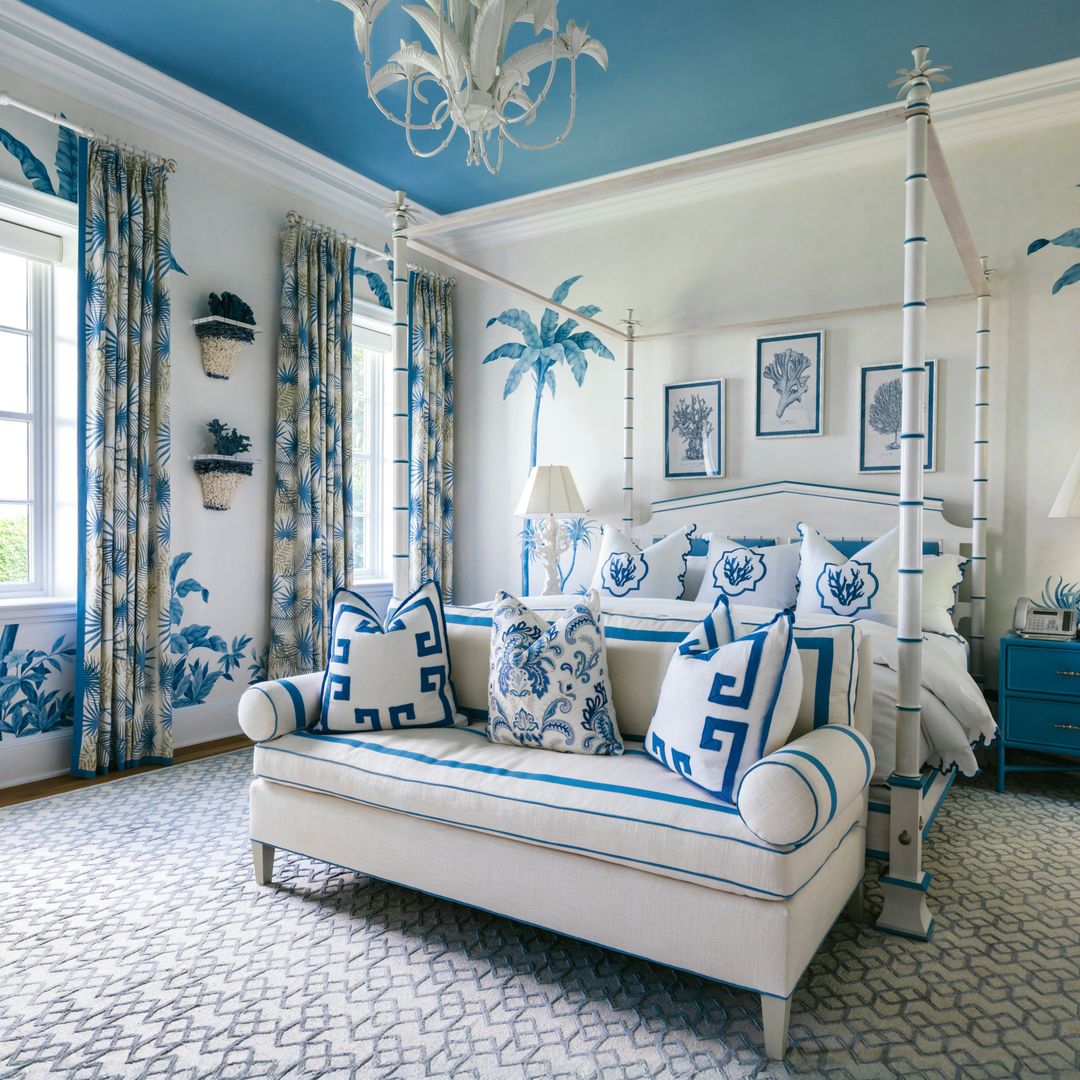 Habitación de dormitorio con cama de matrimonio, sofá y decoración tropical en todos azules y blancos