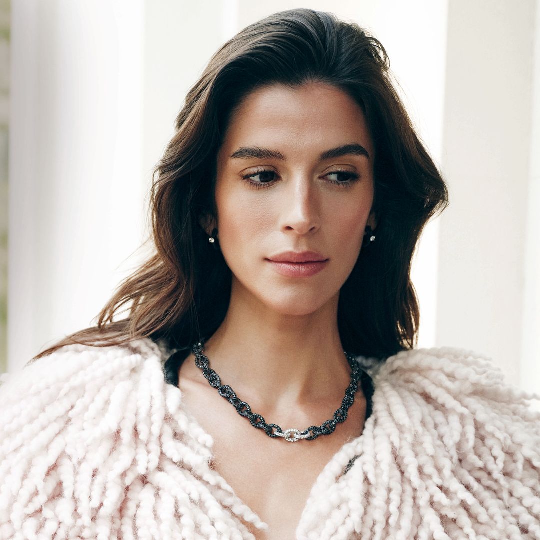 Sandra Gago con cabello largo, usando un abrigo de pelo blanco y un collar y anillos a juego 