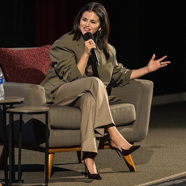 Plano medio de Selena Gomez con traje beige de corte masculino en una charla