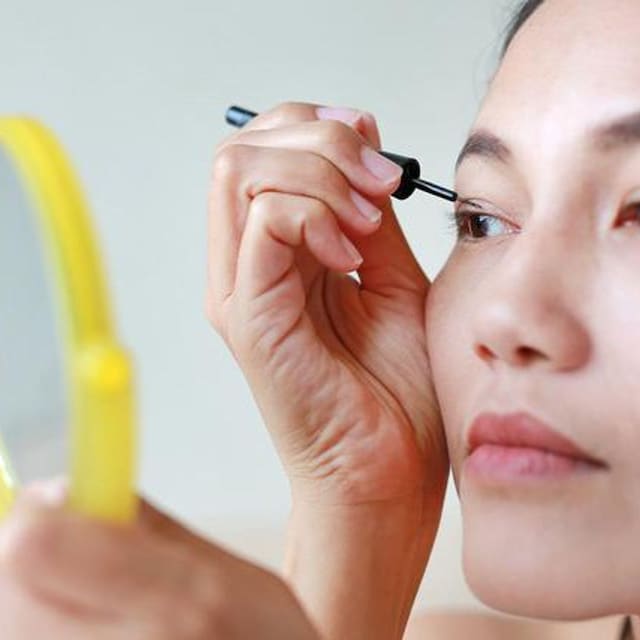 mujer joven delinea sus ojos