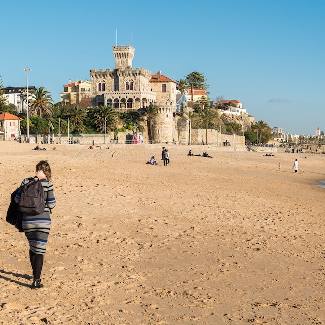 Vista panorámica de la playa de Estoril con una mujer paseando en una soleada tarde de invierno