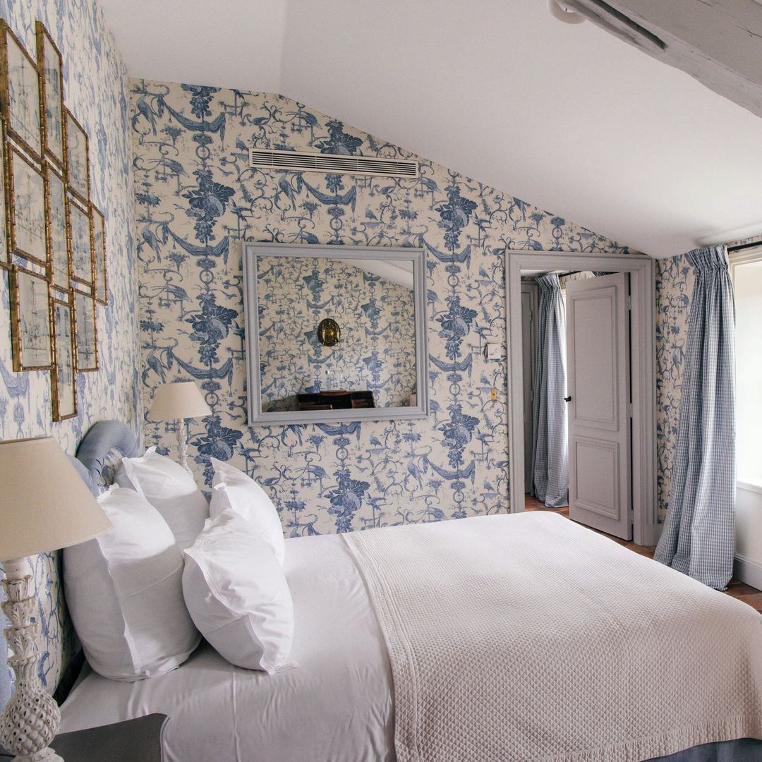 Otra de las habitaciones de la familia, con pared y cabecero tapizados en una tela clásica de patrón botánico, atemporal y elegante